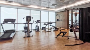 A gym with cardio machines, weightlifting equipment, and a large window offering a view. - Blueground | DIFC, pool, nr Dubai Mall (Dubai)