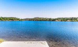A sunny view across the lake from the edge of a dock. - Cozy Mountain Retreat with Hot Tub & Game Room (Groveland)
