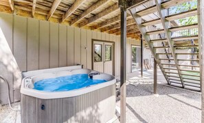 An outdoor hot tub sheltered underneath an elevated wooden deck. - Cozy Mountain Retreat with Hot Tub & Game Room (Groveland)