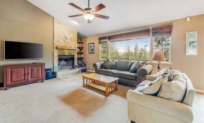 Living room featuring a tall stone fireplace, comfortable seating, and wooded views. - Cozy Mountain Retreat with Hot Tub & Game Room (Groveland)