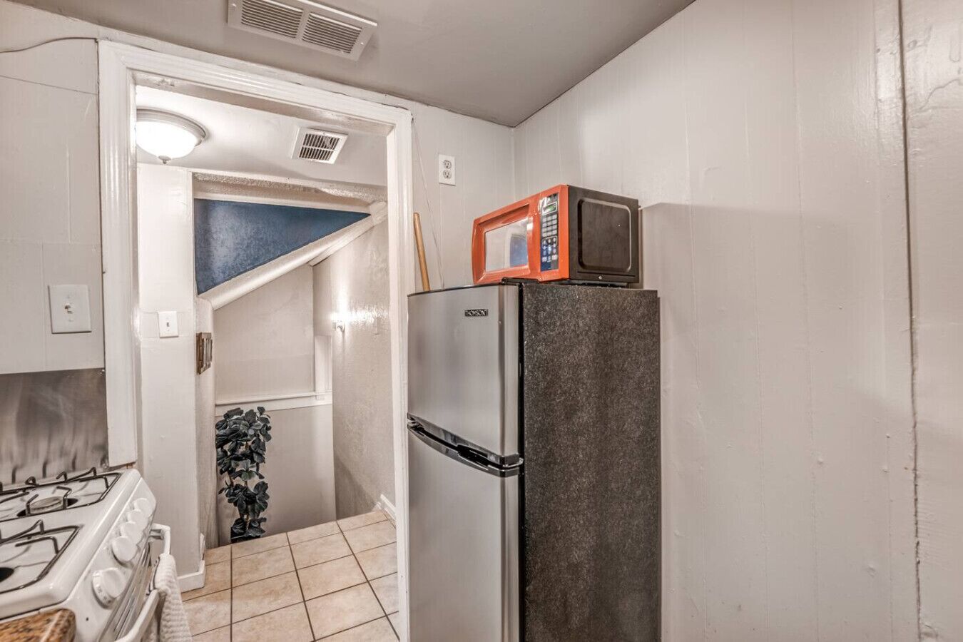 A compact kitchen with a refrigerator, a microwave, and a stove.