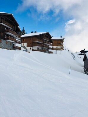 Ein schneebedecktes Skigebiet mit Holzhäusern und blauem Himmel.