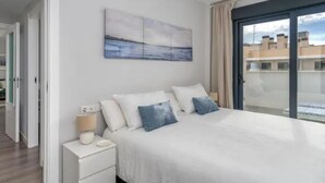 A bedroom with a bed, a nightstand, a lamp, and a painting on the wall. - H2M Pacificio Seaview & Terrace & Common Pool (Malaga)