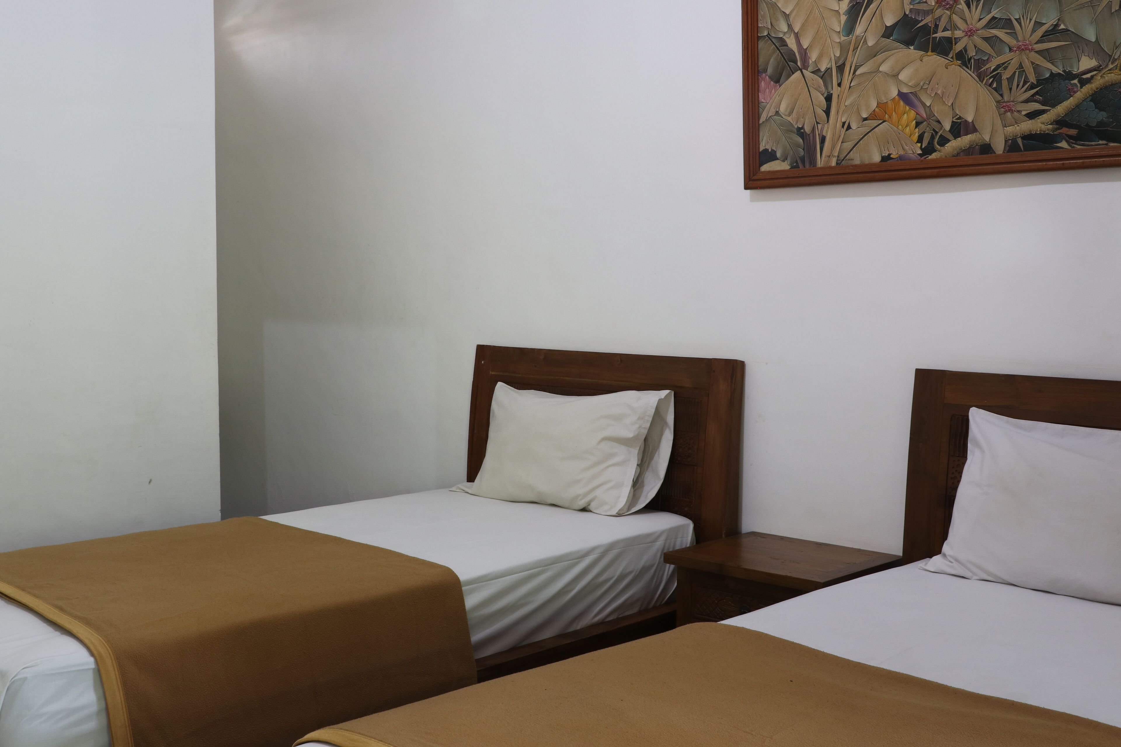 Ein Hotelzimmer mit zwei Einzelbetten, jeweils mit Holz Kopfteilen und weißer Bettwäsche.