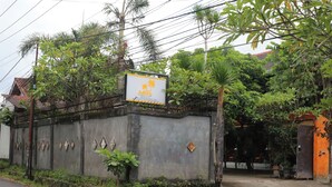 A gated property with a signboard, surrounded by lush greenery and a road. - Adhya Guest House (Mataram)