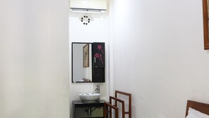 A small bathroom with a white sink, a mirror, and a wooden chair. - Adhya Guest House (Mataram)