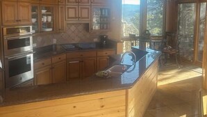 Une cuisine dotée de meubles en bois, d’appareils électroménagers en acier inoxydable et d’une grande fenêtre offrant une vue dégagée.