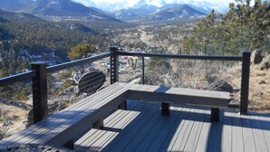 Une terrasse en bois avec des bancs, offrant une vue sur un paysage montagneux.