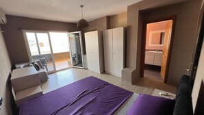 Un dormitorio con una cama grande, un sofá, un armario y un ventanal corredero que da a un balcón.