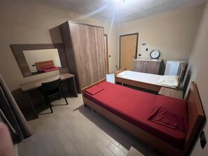A small, compact room with a single bed, a desk, and a wardrobe.