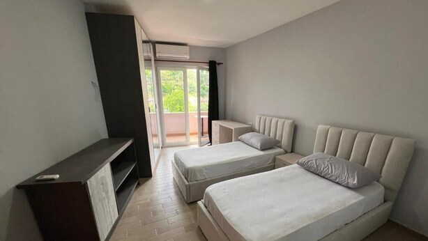 Un dormitorio con dos camas, un escritorio y puerta corrediza de vidrio a un balcón.