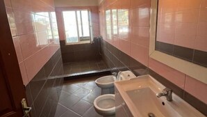 Un baño moderno con dos inodoros, un lavabo y una zona de ducha.