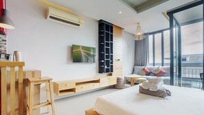 A modern hotel room with a large bed, a wooden console table, a TV, and a large window with a view. - 405 Relife , 5 Minutes Walk To Nai Harn Beach (Rawai)