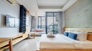 A modern hotel room with a large bed, a desk, a TV, and a balcony with a view. - 405 Relife , 5 Minutes Walk To Nai Harn Beach (Rawai)