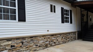Una casa con cimientos de piedra y revestimiento blanco.