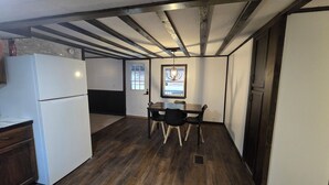 Una cocina compacta con refrigerador, una mesa de comedor con sillas y una ventana con vistas.