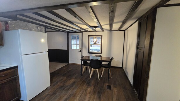 Una cocina compacta con refrigerador, una mesa de comedor con sillas y una ventana con vistas.