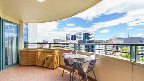 A balcony with a table and chairs, a wooden bench, and a city view. - Central 2BR apartment, Hotel vibe, Walk everywhere (Braddon)