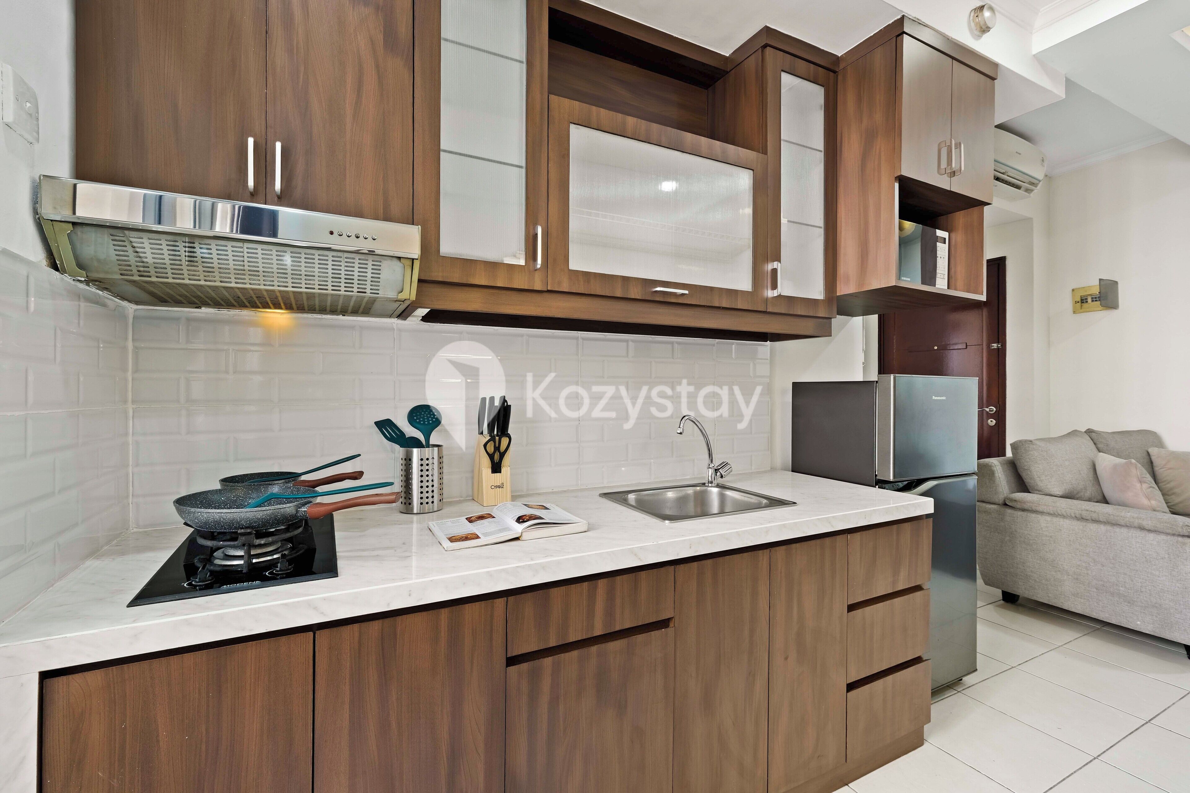 A modern kitchen with wooden cabinets, a stainless steel range hood, a built-in stove, a sink, and a refrigerator.