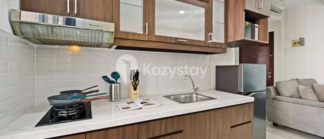 A modern kitchen with wooden cabinets, a stainless steel range hood, a built-in stove, a sink, and a refrigerator.