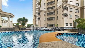 Une piscine dont le fond est recouvert de carreaux décoratifs, entourée d’une terrasse en pierre et d’une allée en bois.