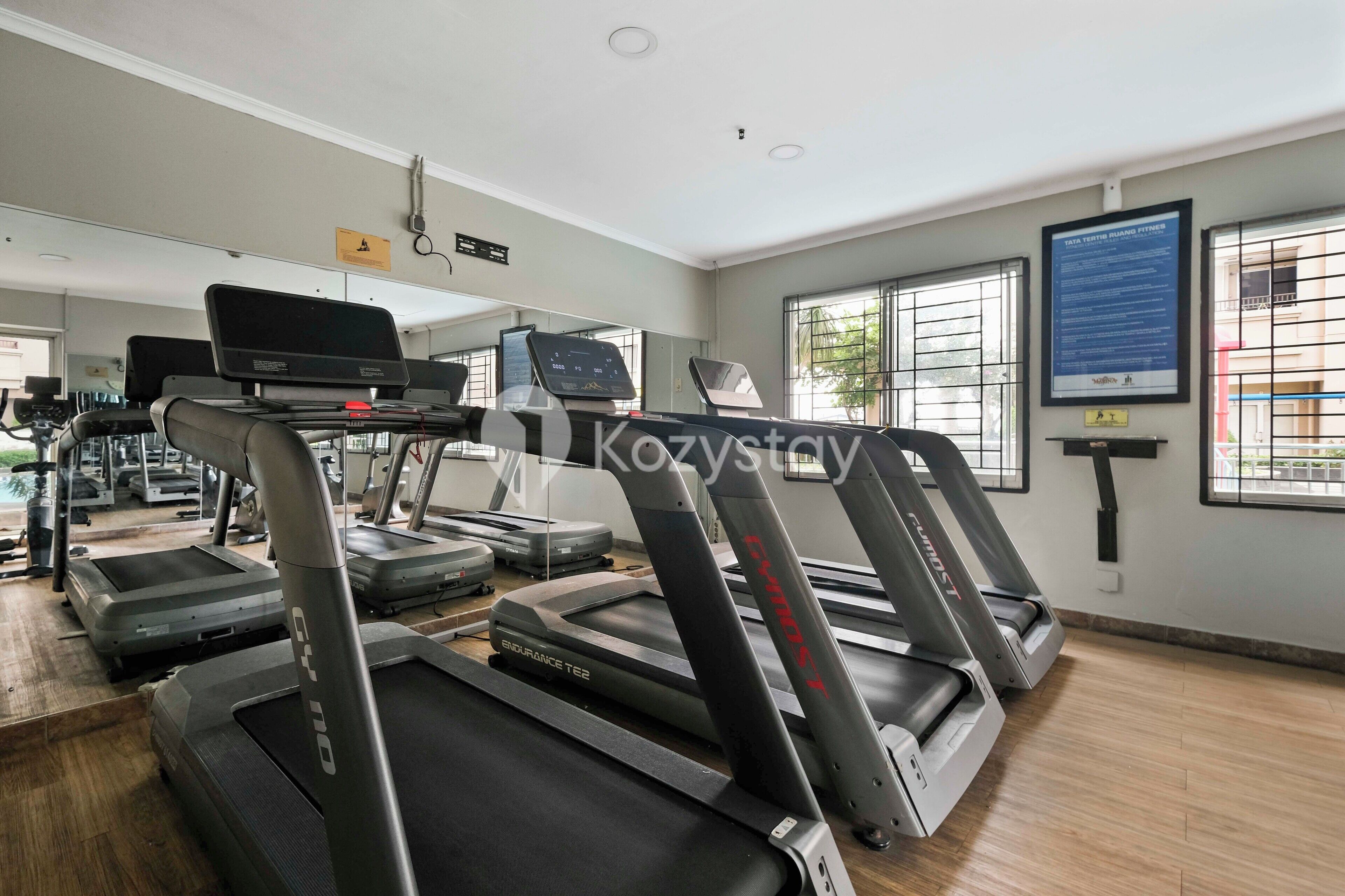Un gimnasio con cintas de correr, bicicletas estáticas y un espejo grande.