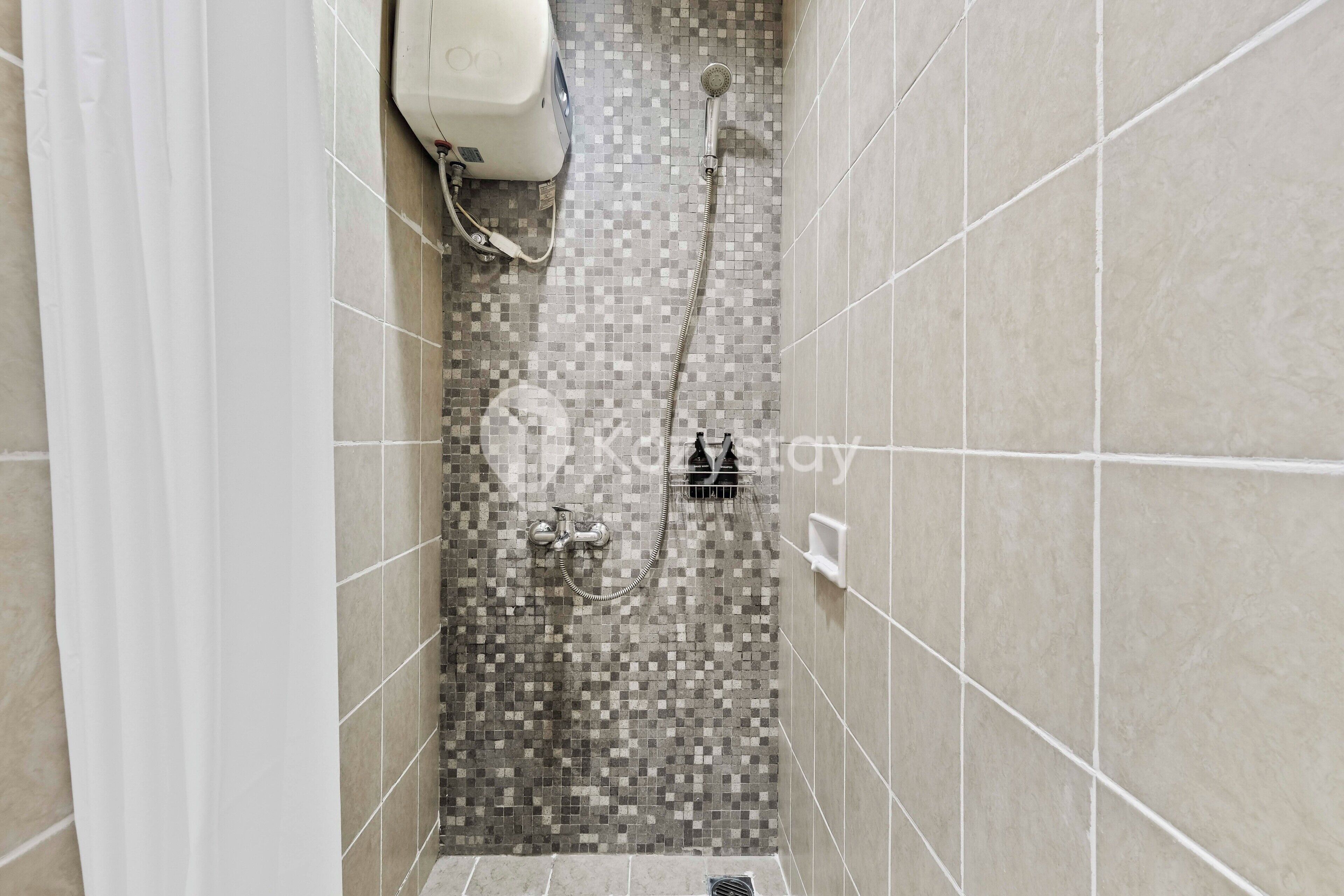 A shower area with tiled walls, a showerhead, and a handheld shower attachment.
