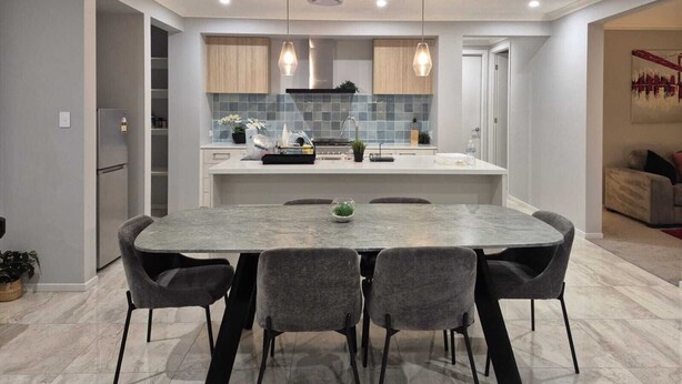 Une cuisine moderne dotée d’un îlot central, de luminaires suspendus et d’un coin repas avec quatre chaises.