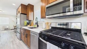 A modern kitchen with wooden cabinets, stainless steel appliances, and a central island. - Efficiency Flat (McKinleyville)