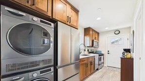 A compact kitchen with a built-in washer and dryer, wooden cabinets, and a microwave. - Efficiency Flat (McKinleyville)