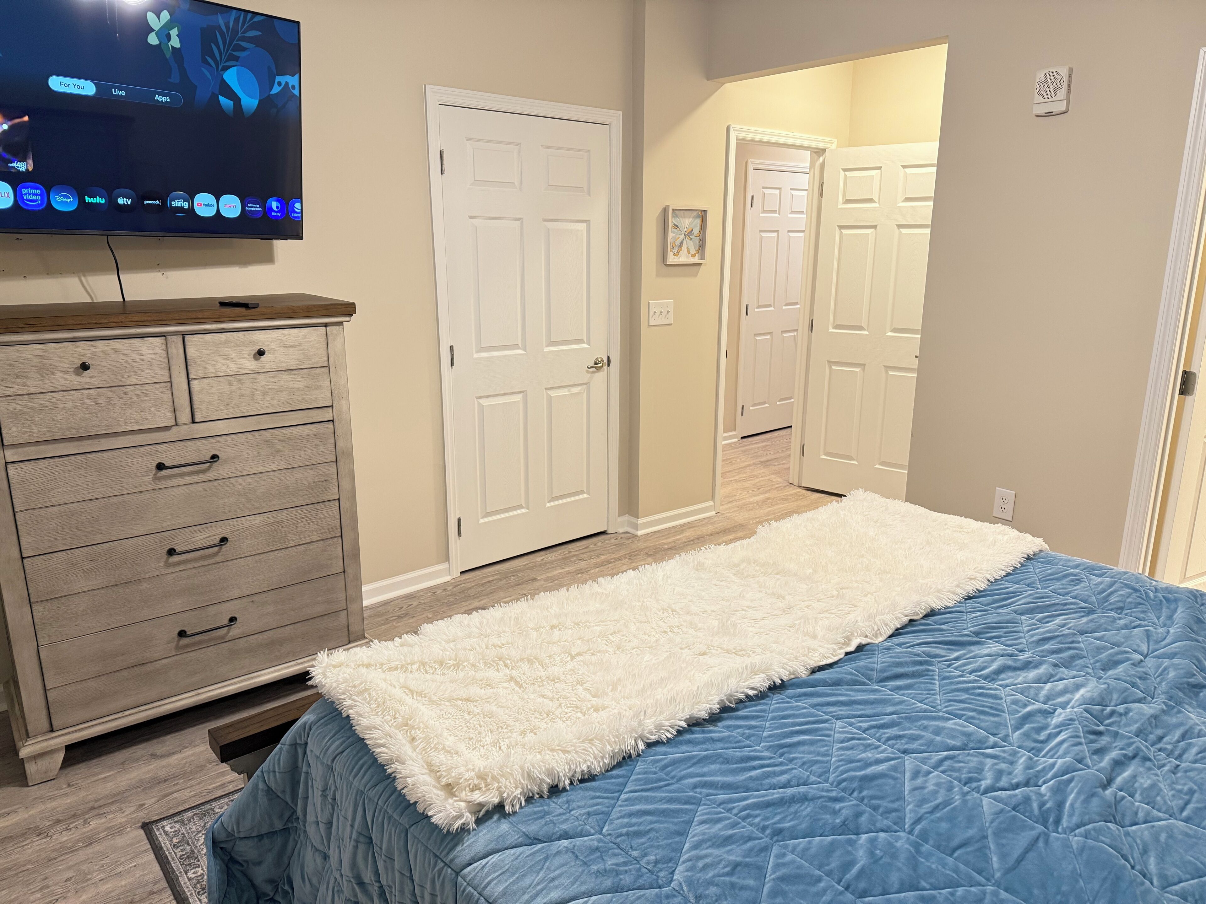 A bedroom with a bed, dresser, and TV.