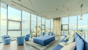 A modern interior with large windows, a sofa, and a view of the city. - The Base Pattaya | Top Location & Utility Include (Bang Lamung, Muang Pattaya)