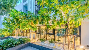 A modern building with glass windows, outdoor seating, and greenery. - The Base Pattaya | Top Location & Utility Include (Bang Lamung, Muang Pattaya)