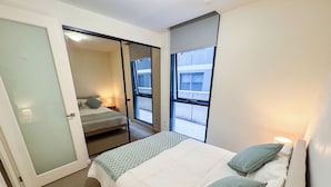 A bedroom with a bed, a window, and a door. - Modern CBD Apartment | Pool, Sauna & Laneway Dining (Melbourne)