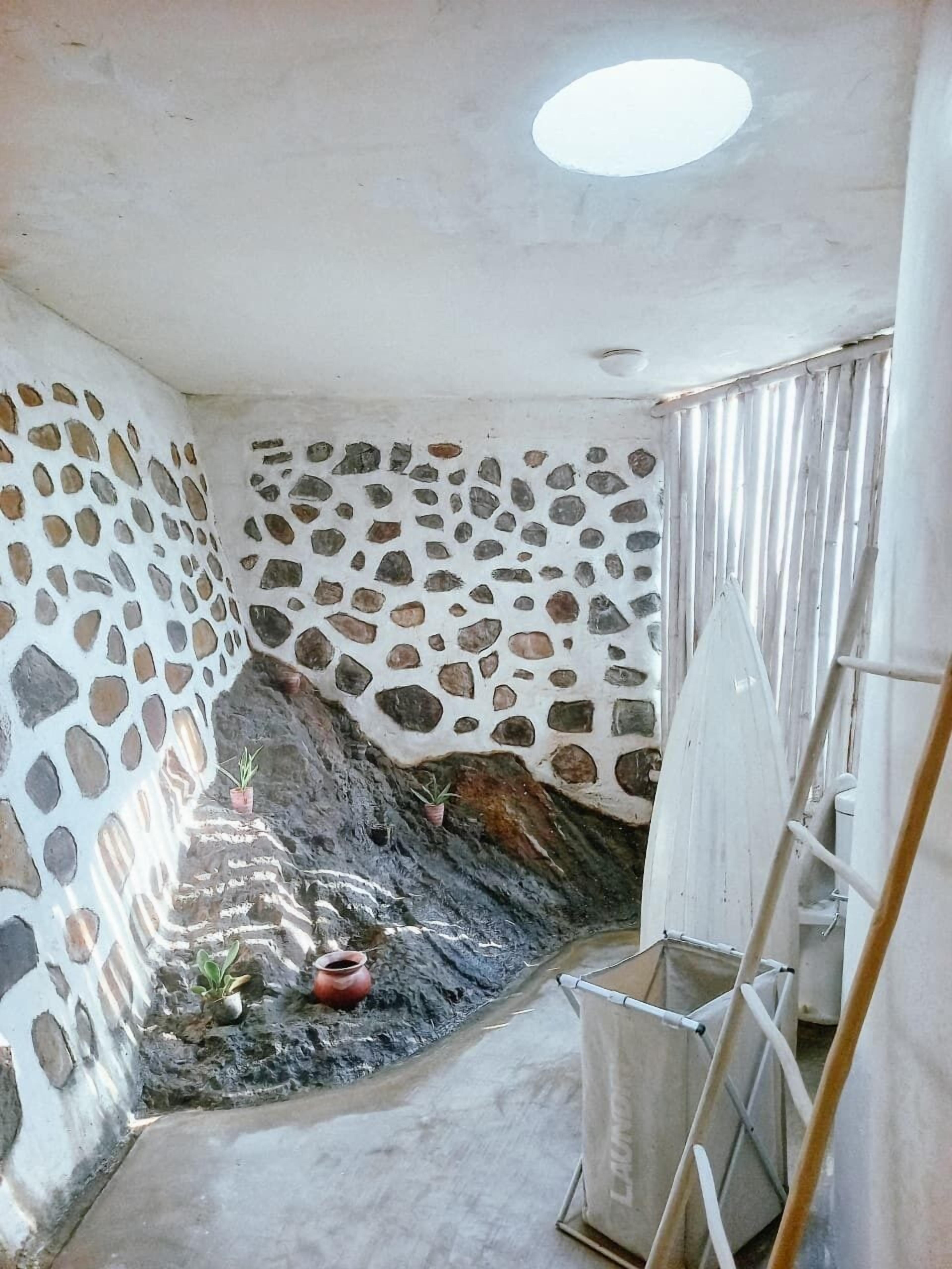 A room with a stone wall, a small window, and a ladder.