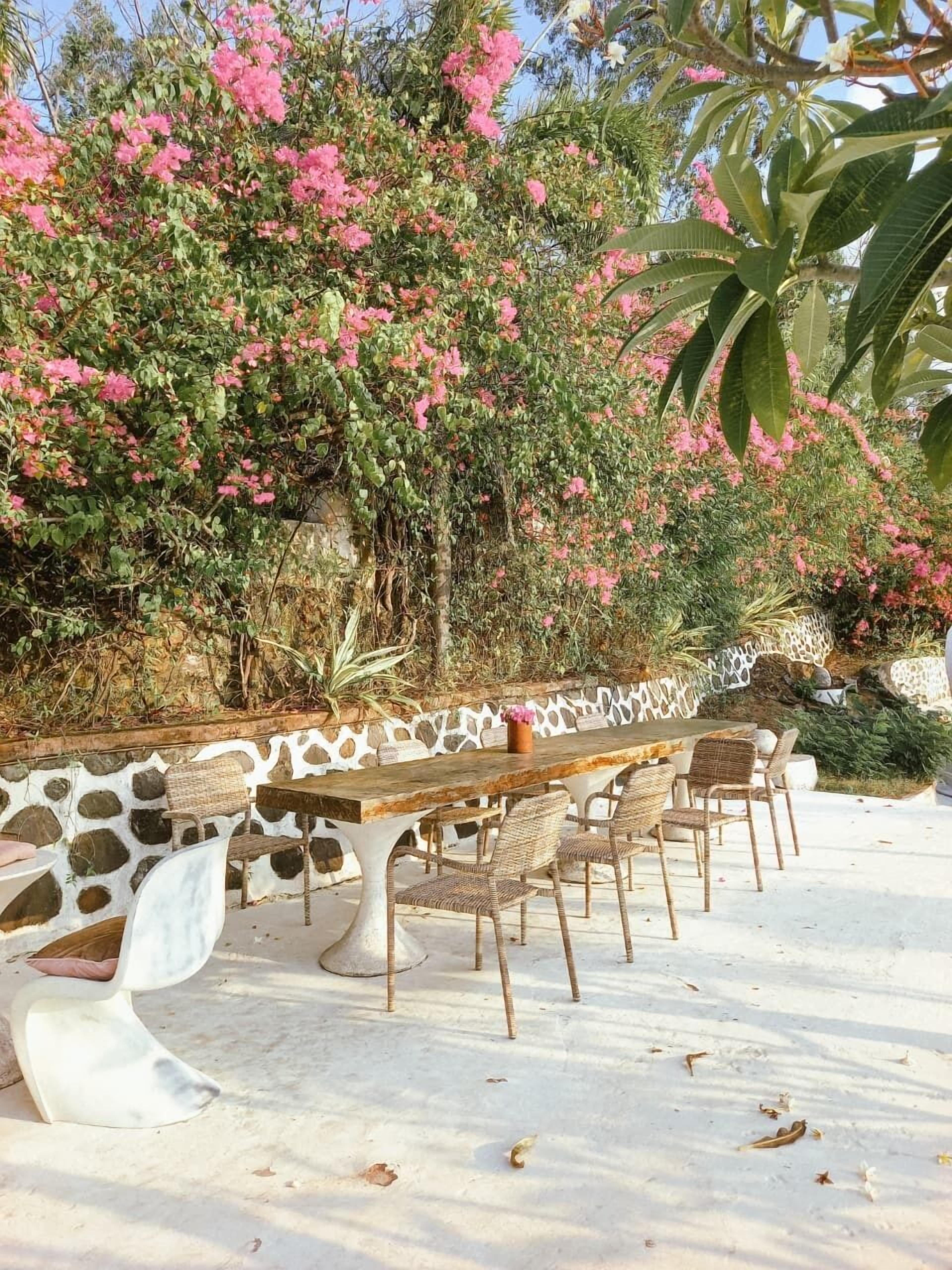 Un espace de restauration en plein air, avec un mur en pierre et une table dressée pour six personnes.