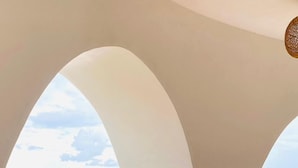 A room with a view of the sea, featuring a curved white wall and a wooden stool. - Mentigibay Dome Villa Lombok (Pemenang)
