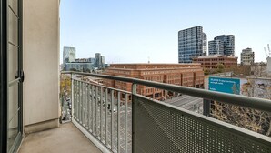 A cityscape with modern buildings, a clear sky, and a balcony with a metal railing. - Family Unit With Balcony, Free Trams to CBD Sights (Melbourne)