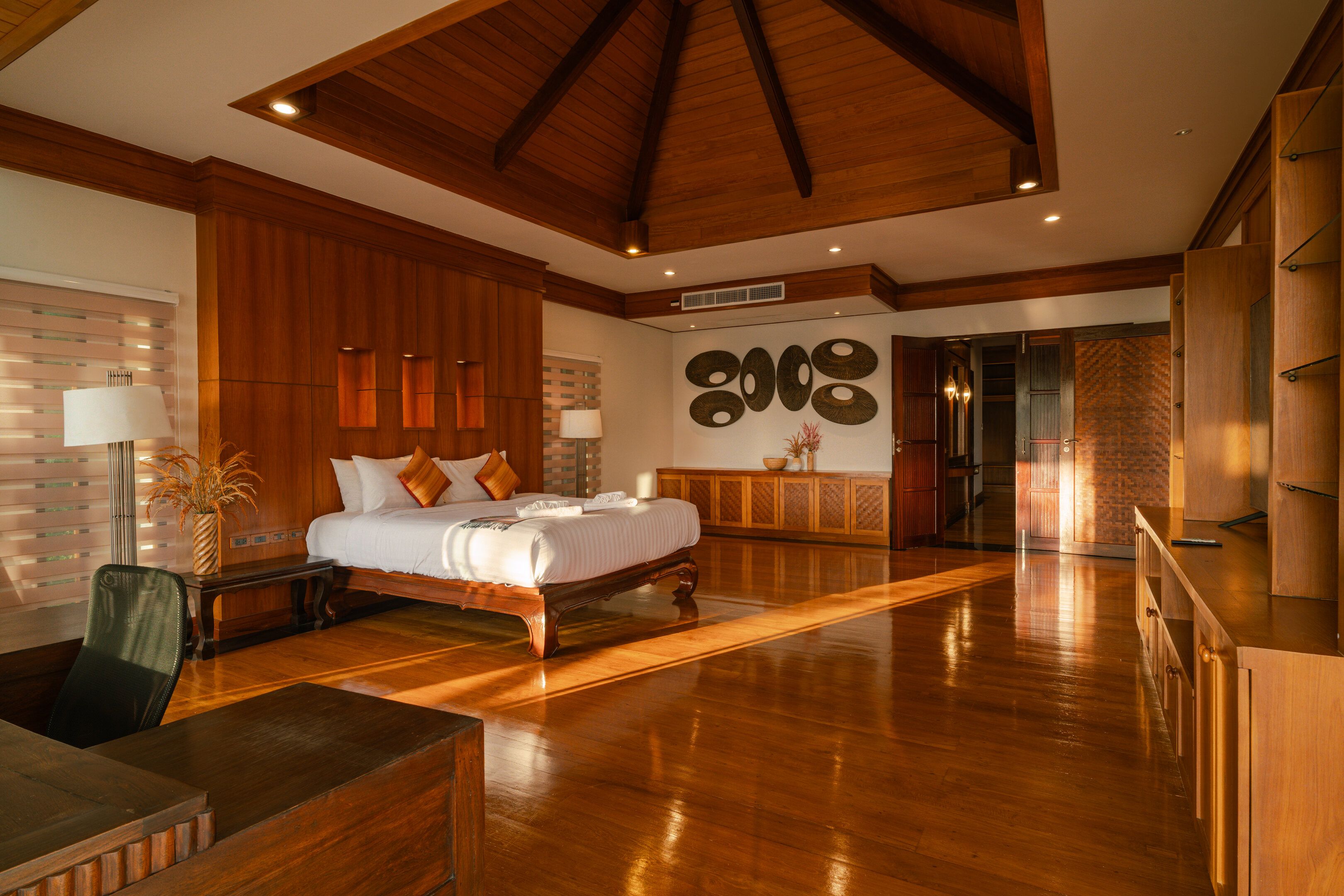 Quarto amplo com cama grande, teto de madeira e vista para o banheiro.