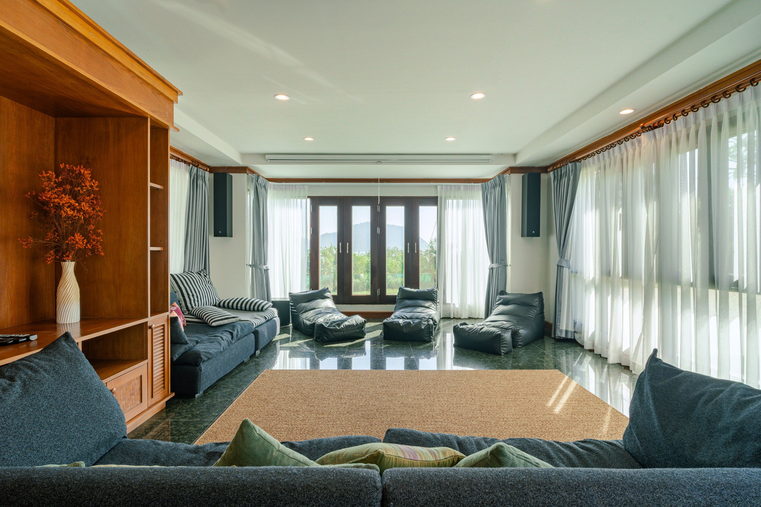 Un salón amplio con un gran sofá, un mueble de madera y vistas a través de un ventanal.