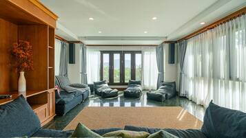 Un salón amplio con un gran sofá, un mueble de madera y vistas a través de un ventanal.