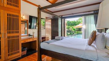 Habitación de hotel con cama, escritorio, televisor y vista a una piscina al aire libre.