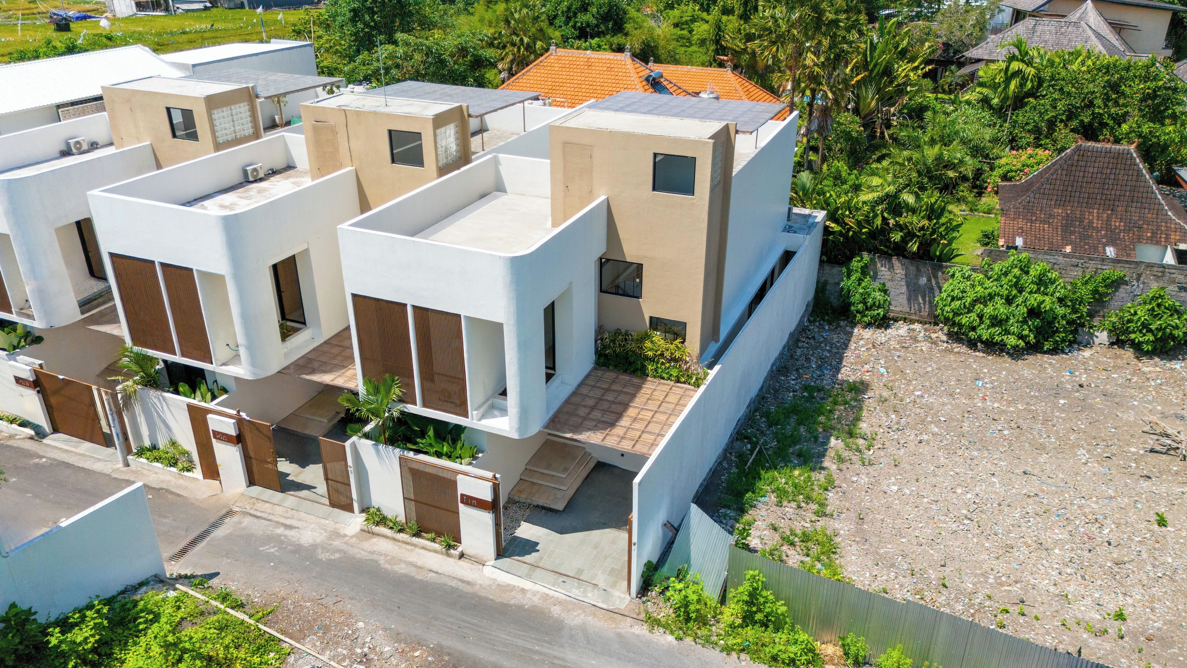 A modern residential building with multiple units, a gated entrance, and a surrounding green area.