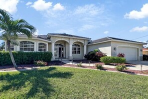 A two-story house with a garage, a front entrance, and a well-maintained lawn. - Boaters Dream, S. Terr, Pool, Yacht Club, Boating (Cape Coral)