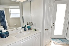 A bathroom with a white sink, mirror, and a door leading to another room. - Boaters Dream, S. Terr, Pool, Yacht Club, Boating (Cape Coral)
