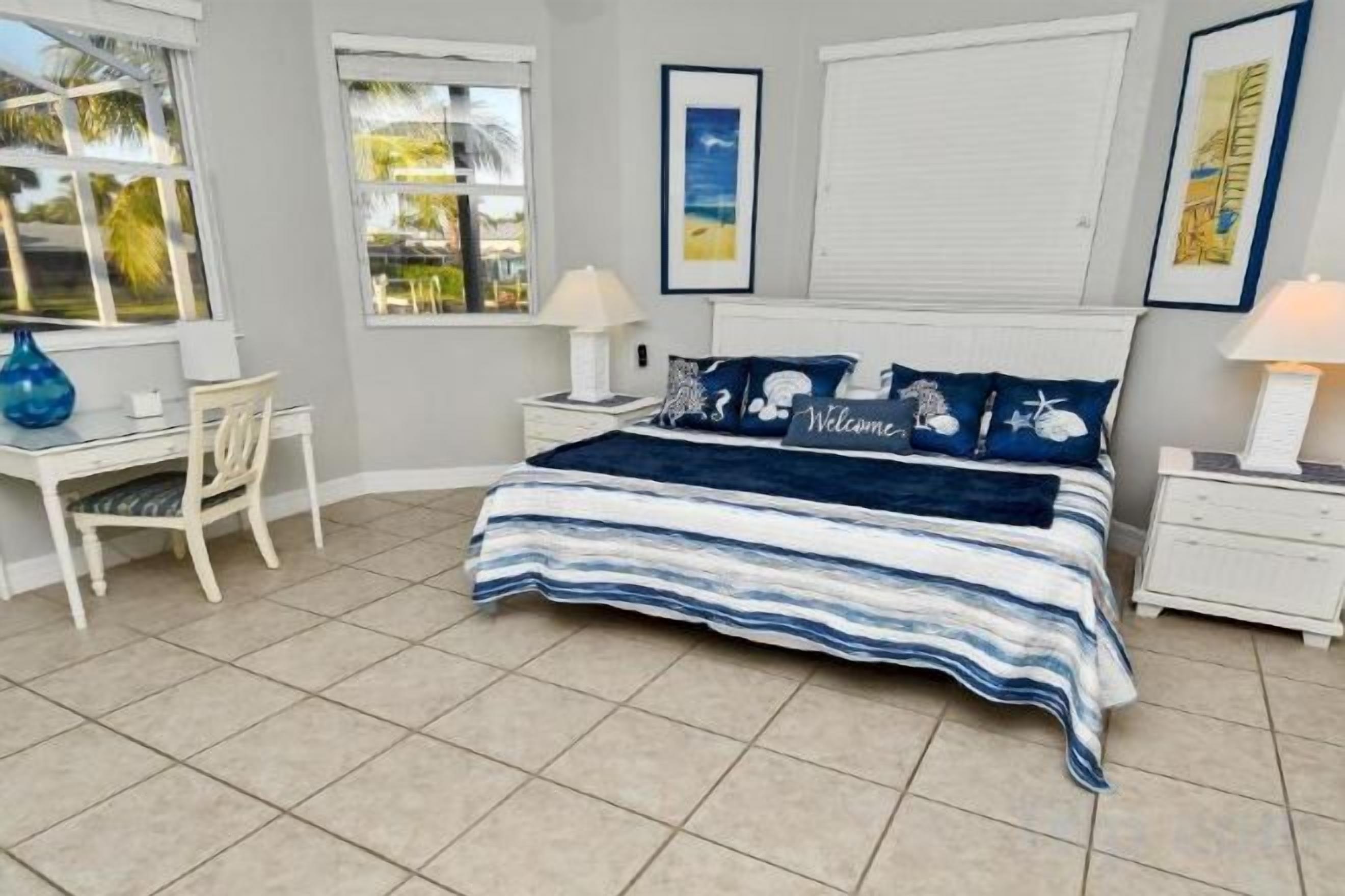 A bedroom with a bed, bedside tables, a desk, and chairs.