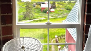 A room with a large arched window offering a view of a rural landscape with barns and fields. - Famous tranquil GreenBluff barn on 10 acres, huge views, north Spokane (Colbert)