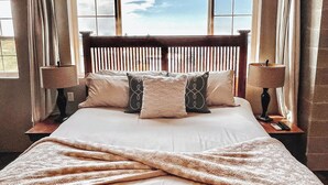 A bed with a wooden headboard, two bedside lamps, and a view of the sky through a window with blinds. - Famous tranquil GreenBluff barn on 10 acres, huge views, north Spokane (Colbert)