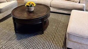 Ein Wohnzimmer mit Kamin, einer Sofagarnitur, einem Couchtisch mit Sonnenblumen und Wanddekoration mit Sonnenblumen.