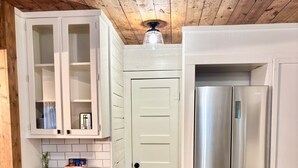 Eine Küche mit Holzboden, weißen Schränken, einem Edelstahlkühlschrank und einer Holzziel.